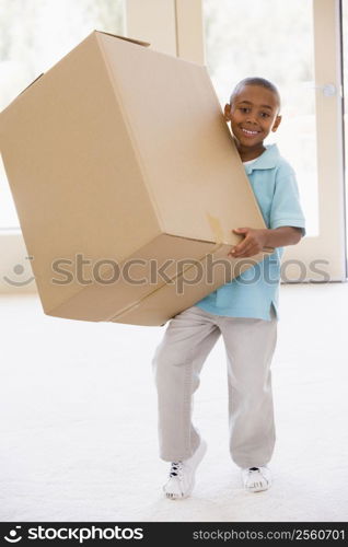 Young boy holding box in new home smiling