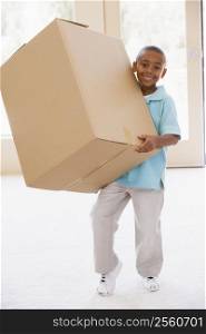 Young boy holding box in new home smiling