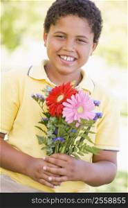 Young boy holding flowers and smiling
