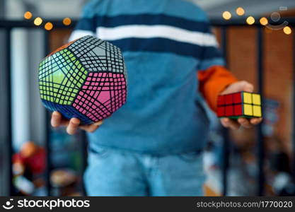 Young boy holds puzzle cubes in his hands. Toy for brain and logical mind training, creative game, solving of complex problems. Young boy holds puzzle cubes in his hands