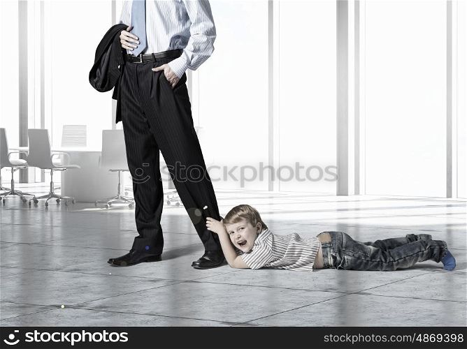 Young boy hugging his father&amp;#39;s leg and crying