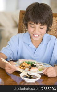 Young boy in dining room eating chinese food smiling