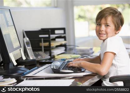 Young boy in home office with computer smiling