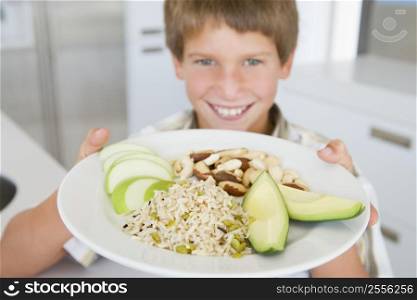 Young boy in kitchen eating rice fruit and nuts smiling