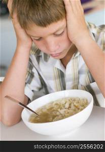 Young boy in kitchen eating soup