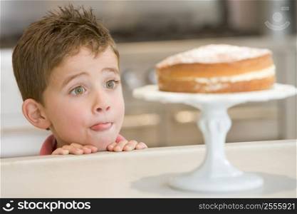 Young boy in kitchen looking at cake on counter