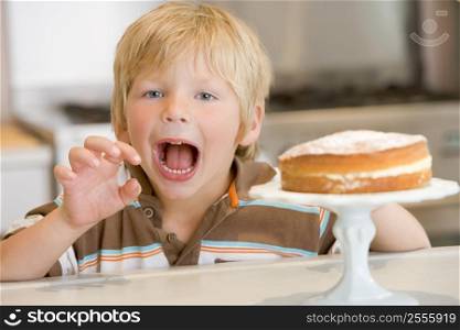Young boy in kitchen with cake on counter