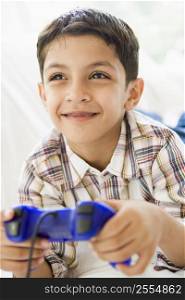 Young boy in living room playing video games and smiling (high key/selective focus)