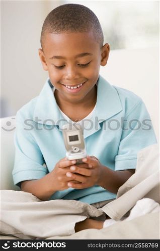 Young boy in living room using cellular phone and smiling