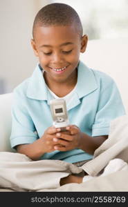 Young boy in living room using cellular phone and smiling