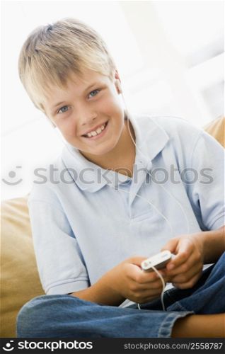 Young boy in living room with MP3 player smiling
