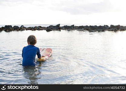 Young boy in sea with bodyboard, Kauai, Hawaii, USA