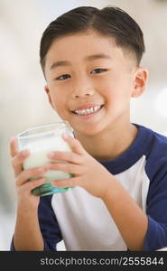 Young boy indoors drinking milk smiling