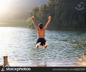 Young boy jumping into lake