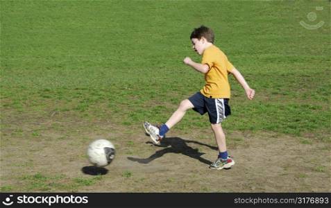 Young boy kicking soccer ball