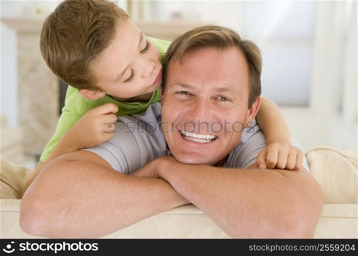 Young boy kissing smiling man in living room