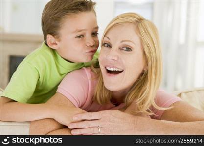 Young boy kissing smiling woman in living room
