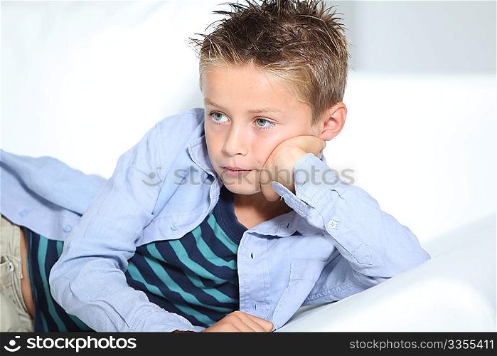 Young boy laying on a sofa at home