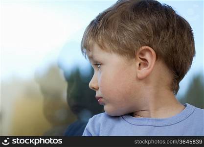 Young boy looking back at shadow in glass