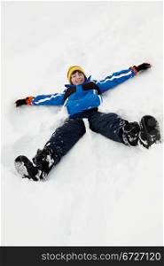Young Boy Making Snow Angel On Slope