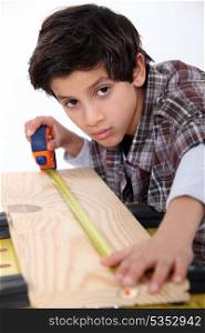 Young boy measuring a plank of wood