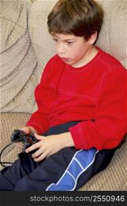Young boy playing a video game sitting on a couch