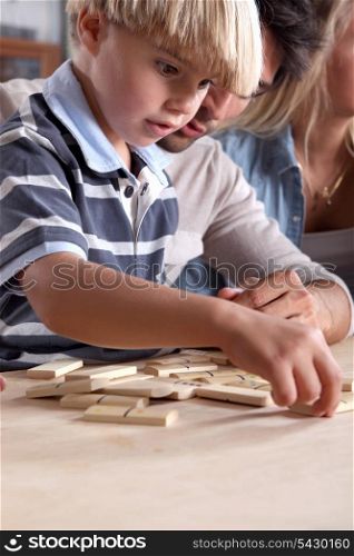 Young boy playing dominoes with his father