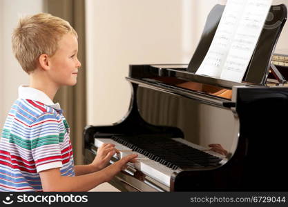 Young boy playing grand piano at home