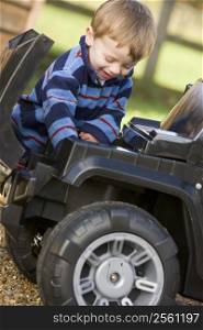 Young boy playing outdoors with toy truck smiling