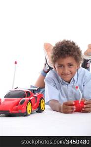 Young boy playing with a red remote control sports car