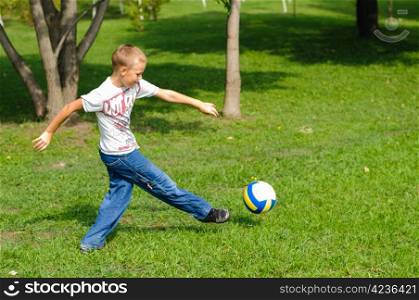 Young boy playing with his ball in the grass outdoors