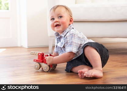 Young Boy Playing With Wooden Toy Car At Home