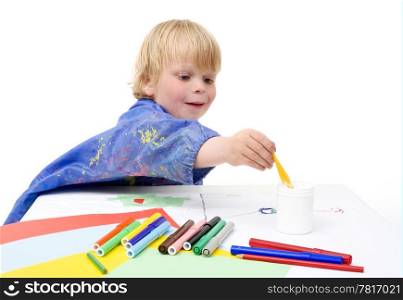 Young boy reaching for the jar with glue across the table