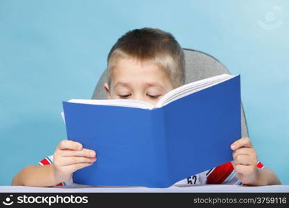 Young boy reading a book, child kid on blue background holding an open book