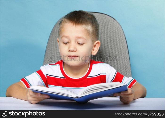 Young boy reading a book, child kid on blue background holding an open book