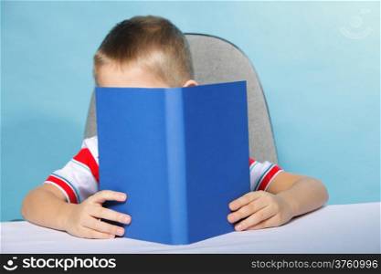 Young boy reading a book, child kid on blue background holding an open book