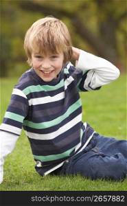 Young Boy Relaxing Outdoors Sitting On Grass