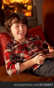 Young Boy Relaxing With MP3 Player By Cosy Log Fire