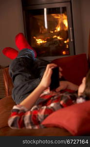 Young Boy Relaxing With MP3 Player By Cosy Log Fire