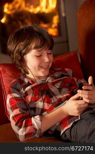 Young Boy Relaxing With MP3 Player By Cosy Log Fire