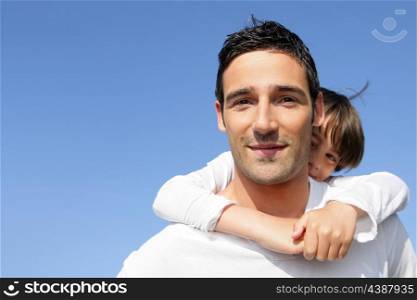 Young boy riding piggy-back on his father&rsquo;s back