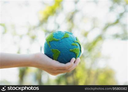 Young boy&rsquo;s hand holding planet Earth globe at natural park background as Earth day to save this planet with ESG principle and environment friendly energy for brighter future. Gyre. Young boy hand holding planet Earth globe at natural park background. Gyre