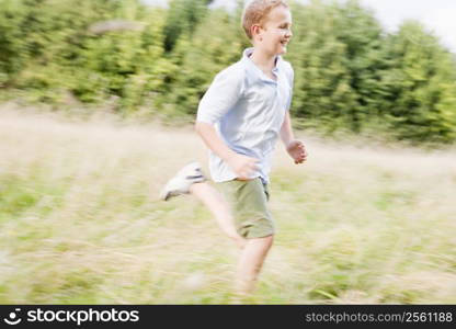 Young boy running in a field smiling