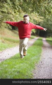 Young boy running on path outdoors smiling (selective focus)