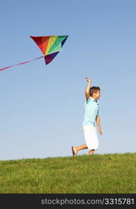 Young boy runs with kite through field