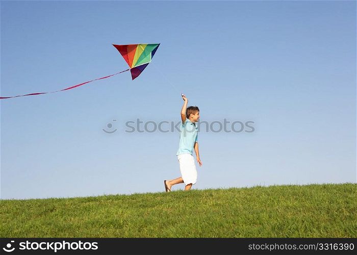 Young boy runs with kite through field