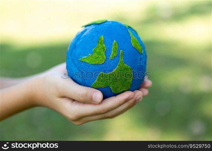 Young boy’s hand holding planet Earth globe at natural park background as Earth day to save this planet with ESG principle and environment friendly energy for brighter future. Gyre. Young boy hand holding planet Earth globe at natural park background. Gyre