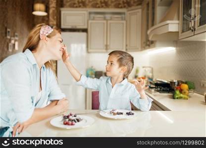 Young boy shows sandwiches with natural melted chocolate. Cute male kid cooking on the kitchen. Happy child prepares and tastes sweet dessert at the table. Young boy shows sandwiches with melted chocolate