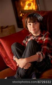Young Boy Sitting On Sofa By Cosy Log Fire