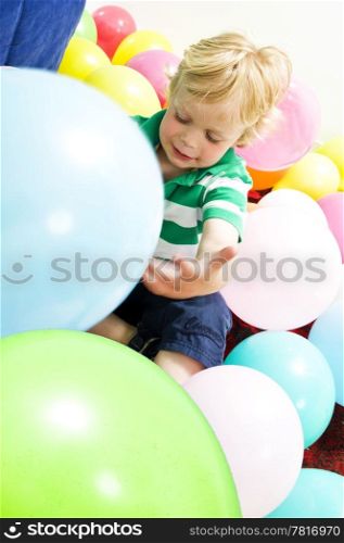 Young boy sitting on the floor, playing with balloons